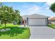 Charming home featuring a two-car garage, well-kept lawn, and flowering trees at 419 Wellesly Dr, Davenport, FL 33897