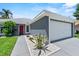 Exterior view of home featuring a red front door, two-car garage, and decorative landscaping at 419 Wellesly Dr, Davenport, FL 33897