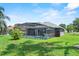 Relaxing screened-in pool area with lush green grass and a view of the home's exterior at 419 Wellesly Dr, Davenport, FL 33897