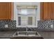 Stainless steel sink under window with black backsplash and brown cabinets at 452 Lake Suzanne Dr, Lake Wales, FL 33859