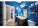 This bathroom features blue walls, wood floor, shelves, and granite countertop at 4662 Osprey Way, Winter Haven, FL 33881
