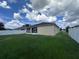 Backyard featuring well-maintained lawn, white fence, screened patio and house exterior at 4747 Mandolin Loop, Winter Haven, FL 33884