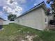 Side view of backyard with green grass, white fence and stucco exterior of the home at 4747 Mandolin Loop, Winter Haven, FL 33884