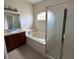Bathroom featuring a bathtub, vanity with sink, framed mirror, and glass enclosed shower at 4747 Mandolin Loop, Winter Haven, FL 33884