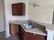 Kitchenette area featuring dark wood cabinets, laminate countertops, and stainless steel sink at 4747 Mandolin Loop, Winter Haven, FL 33884