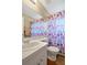 Bright bathroom features a white sink, toilet, large mirror, and a colorful shower curtain at 5424 Moon Valley Dr, Lakeland, FL 33812