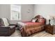 Cozy bedroom with a patterned bedspread, comfortable armchair, and natural light from the window at 545 Pond Cypress Ct, Auburndale, FL 33823