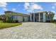 Stunning single-story home features a brick driveway, lush landscaping, and a welcoming covered porch at 545 Pond Cypress Ct, Auburndale, FL 33823