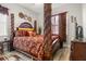 Opulent main bedroom featuring a four-poster bed, warm color scheme, and elegant decor at 545 Pond Cypress Ct, Auburndale, FL 33823