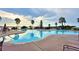 Community pool with lake view, palm trees and lounge chairs at 545 Pond Cypress Ct, Auburndale, FL 33823