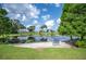 Scenic view of a serene pond with a bench, lush greenery, and surrounding houses at 6027 Grand Oaks Se Dr, Winter Haven, FL 33884