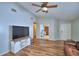 Spacious living room showcasing hardwood floors, a ceiling fan, and large television at 658 Lake Dexter Cir, Winter Haven, FL 33884