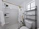 This well-lit bathroom features a shower, toilet, and convenient black shelving for towels and bathroom essentials at 914 Mangham Rd, Babson Park, FL 33827