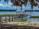 Lake view of the dock with a shelter and seating at the end of a sandy beach at 914 Mangham Rd, Babson Park, FL 33827
