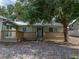 Charming single-story home with a wooden deck and lush tree providing shade, complemented by rock landscaping at 914 Mangham Rd, Babson Park, FL 33827