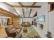 Comfortable living room with exposed beams, a stone fireplace, and open access to the kitchen at 914 Mangham Rd, Babson Park, FL 33827