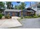 Cozy one-story home with a charming wooden porch, gravel driveway, and lush landscaping at 103 Se Tuscawilla Ave, Ocala, FL 34471