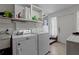 Bright laundry room with modern washer and dryer, convenient sink, storage shelf, and outside access at 103 Se Tuscawilla Ave, Ocala, FL 34471