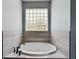 A bathtub features tiled walls, jacuzzi jets and a glass block window for natural light at 1264 Buckeye Ne Rd, Winter Haven, FL 33881