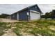 Side exterior view of a blue home with a two-car garage and landscaped yard at 1264 Buckeye Ne Rd, Winter Haven, FL 33881