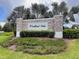 Inviting stone entrance sign to Woodland Oaks, framed by lush landscaping and mature palm trees at 1274 Pintail Pl, Lakeland, FL 33813