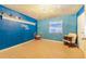 The vibrant blue bedroom showcases wood-look tile floors, a window, and a unique wall decor at 1317 Avenue A Se, Winter Haven, FL 33880
