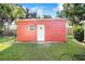 Side exterior view of the red shed with a service door and window at 1317 Avenue A Se, Winter Haven, FL 33880