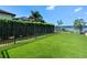 Well-maintained backyard features green artificial grass, a sleek black fence, and stunning lake views at 1836 Woodpointe Dr, Winter Haven, FL 33884