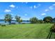 Expansive backyard with lush green lawn, mature trees, and a private dock on the serene lake at 1836 Woodpointe Dr, Winter Haven, FL 33884
