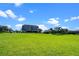 Expansive backyard with lush green lawn and a modern home featuring solar panels and tropical landscaping at 1836 Woodpointe Dr, Winter Haven, FL 33884
