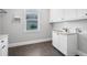 Clean laundry room with white cabinets, granite counters, tile backsplash and dark floors at 1836 Woodpointe Dr, Winter Haven, FL 33884