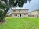 View of the large backyard featuring a two-story home and mature shade tree at 1844 Emily Dr, Winter Haven, FL 33884