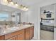 Bright bathroom featuring double sinks, wood cabinets, framed mirror, and an open view into the bedroom at 195 Kissengen Park Blvd, Bartow, FL 33830
