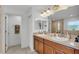 Bright bathroom featuring double sinks, wood cabinets, framed mirror, and a walk-in shower with neutral tile at 195 Kissengen Park Blvd, Bartow, FL 33830