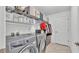 Well-lit laundry room featuring modern appliances, overhead shelving, and neutral tile floors at 195 Kissengen Park Blvd, Bartow, FL 33830
