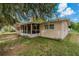 A cozy home featuring a screened porch surrounded by lush greenery and mature trees in the backyard at 208 Lake Dale Dr, Auburndale, FL 33823