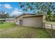 The backyard exterior displays a door to the home and a fenced-in yard with mature trees for added privacy at 208 Lake Dale Dr, Auburndale, FL 33823
