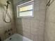 Clean bathroom with window, showerhead, and sleek tiled walls at 217 Shore Loop, Winter Haven, FL 33884
