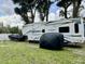 Bighorn RV parked in a grassy area with a boat and other equipment covered nearby at 217 Shore Loop, Winter Haven, FL 33884