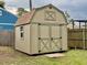 New storage shed with double doors and decorative trim against a blue house backdrop at 217 Shore Loop, Winter Haven, FL 33884