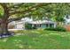 Charming blue home with a well-manicured lawn and a large, mature shade tree in the front yard at 4125 Sunny View Dr, Lakeland, FL 33813