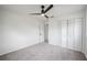 A bright bedroom with neutral carpet, white walls, ceiling fan, and closet doors at 4921 Sharon Ave, Lakeland, FL 33812