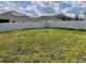 Backyard featuring a full lawn, white fencing, and houses in the background at 516 Ingleside Ln, Haines City, FL 33844