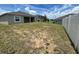 View of the back of the house from the backyard with a full lawn and white fencing at 516 Ingleside Ln, Haines City, FL 33844