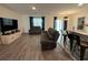 Open living room featuring hardwood floors, a sectional sofa, a TV, and bar seating area at 516 Ingleside Ln, Haines City, FL 33844