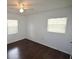 This cozy bedroom features hardwood floors, a ceiling fan, and natural light from two windows at 520 Oakland Rd, Auburndale, FL 33823