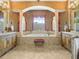 An opulent bathroom features dual vanities, columns, and a large soaking tub under a window at 5200 Pebble Beach Blvd, Winter Haven, FL 33884