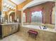 The opulent bathroom features dual vanities, columns, and a large soaking tub under a window at 5200 Pebble Beach Blvd, Winter Haven, FL 33884