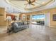 Open-concept living room with travertine floors, a decorative ceiling, and a view of the lake at 5200 Pebble Beach Blvd, Winter Haven, FL 33884