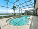 Enjoy the screened-in pool and spa with a view of the lake beyond the landscaping at 5200 Pebble Beach Blvd, Winter Haven, FL 33884